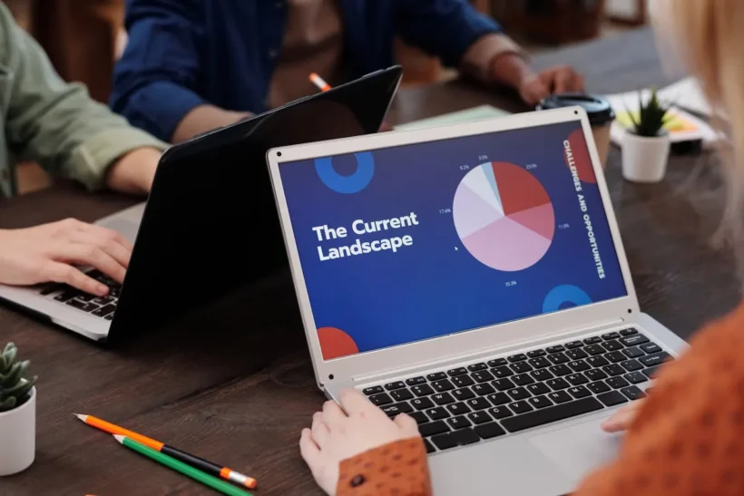 Pessoas trabalhando em escritório com notebook exibindo gráficos e painel de dados, representando cloud computing no varejo e vantagens de softwares de gestão em nuvem.