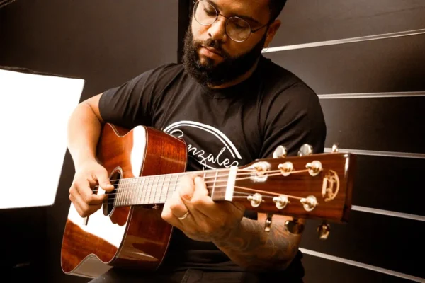Músico tocando violão acústico em estúdio, com expressão concentrada e luz suave, demonstrando como instrumentos acústicos contribuem para momentos de relaxamento
